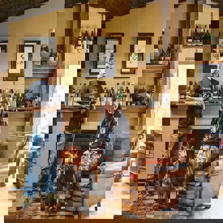 Duncan Forsyth and Anna Riederer infront of a fireplace with a dog