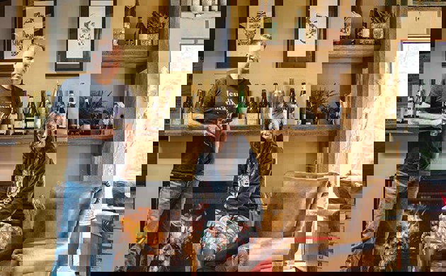 Duncan Forsyth and Anna Riederer infront of a fireplace with a dog