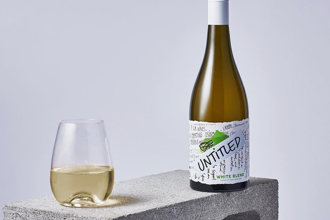 A wine bottle of Untitled Wines' white blend next to a filled glass