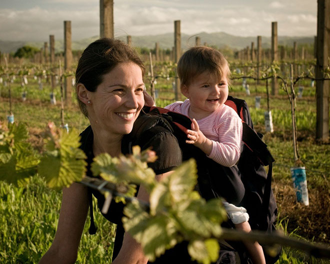 Kirsten Searle planting vines with a baby on her back