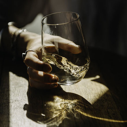 A hand holding a swirling stemless glass of wine