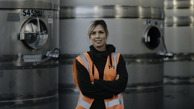 Alice Rule standing infront of tanks in a winery
