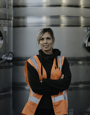 Alice Rule standing infront of tanks in a winery