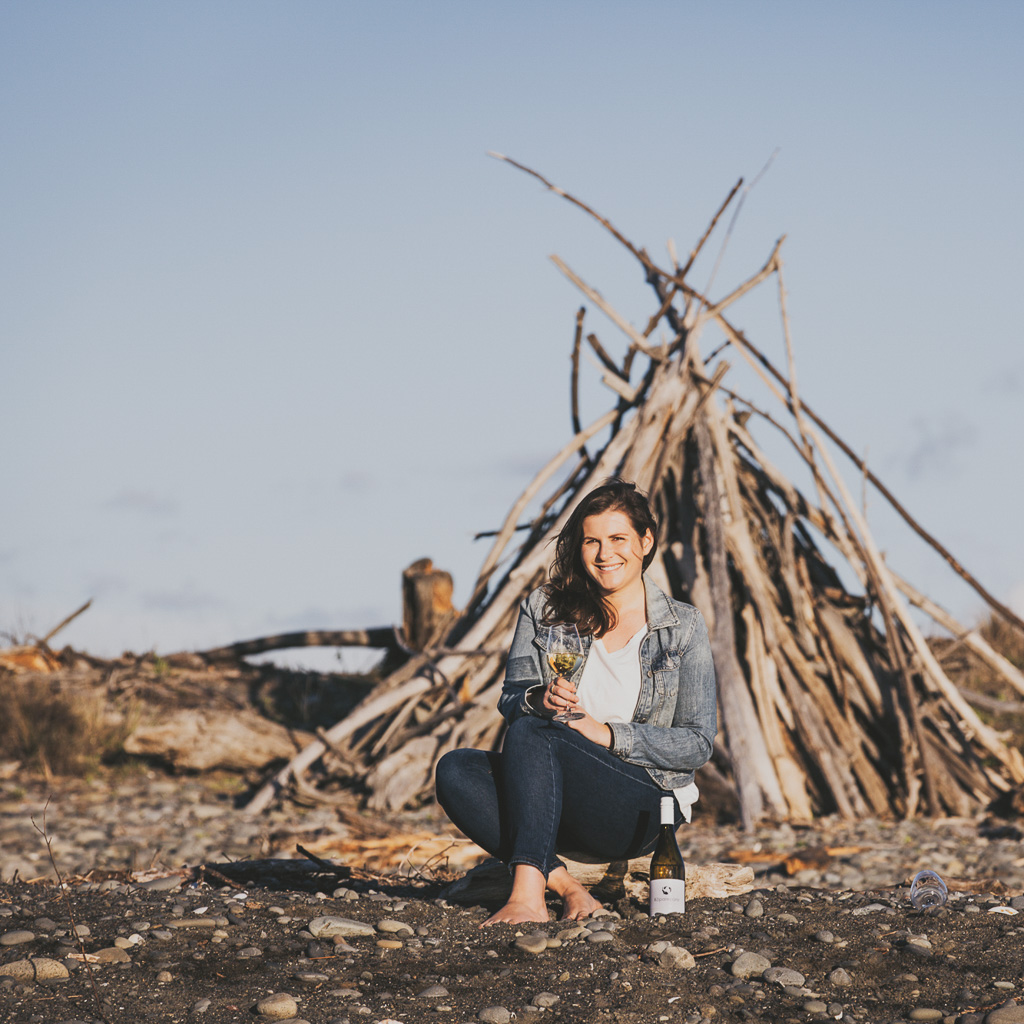 Samantha White sitting on beach with glass of wine