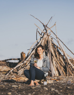 Samantha White sitting on beach with glass of wine