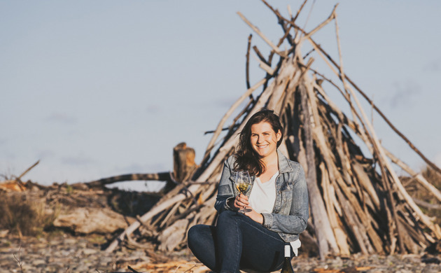 Samantha White sitting on beach with glass of wine