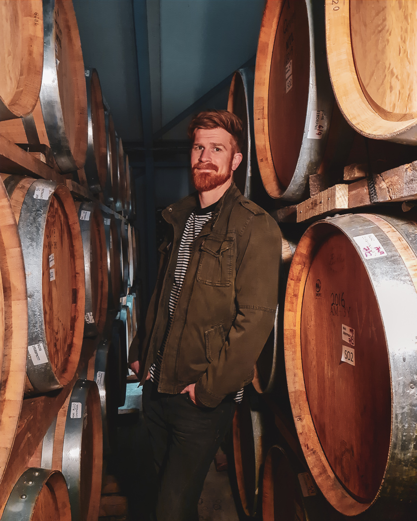 Brad Frederickson standing between wine barrels