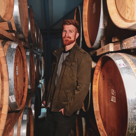 Brad Frederickson standing between wine barrels