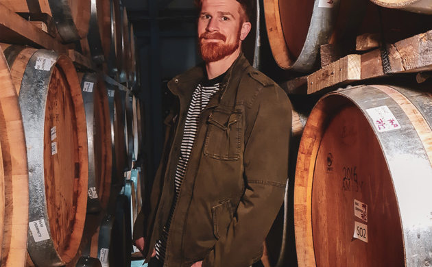 Brad Frederickson standing between wine barrels