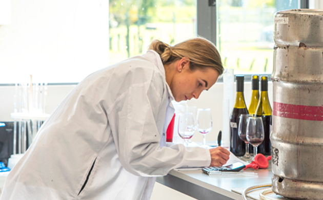 Girl in lab coat with wine bottles