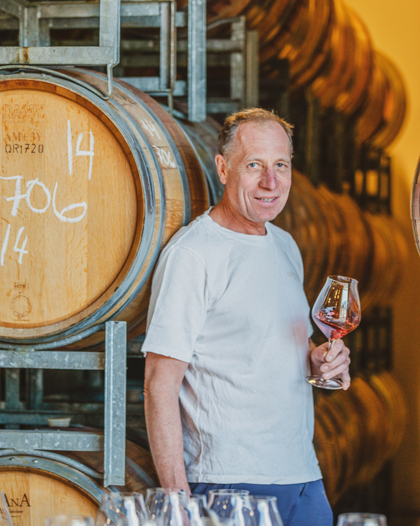 Rudi Bauer standing by wine barrels