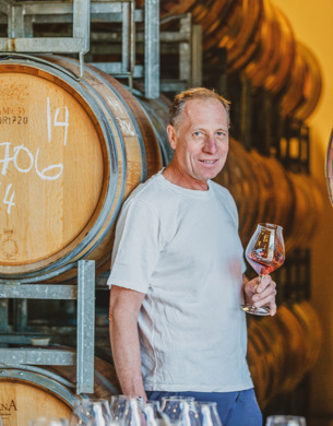 Rudi Bauer standing by wine barrels