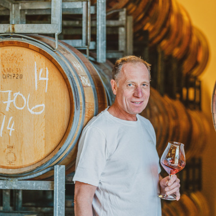 Rudi Bauer standing by wine barrels