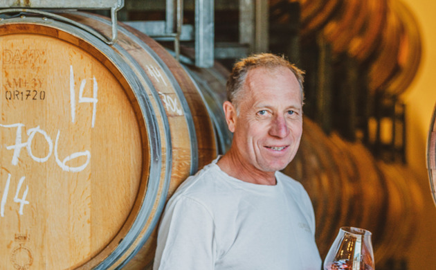Rudi Bauer standing by wine barrels