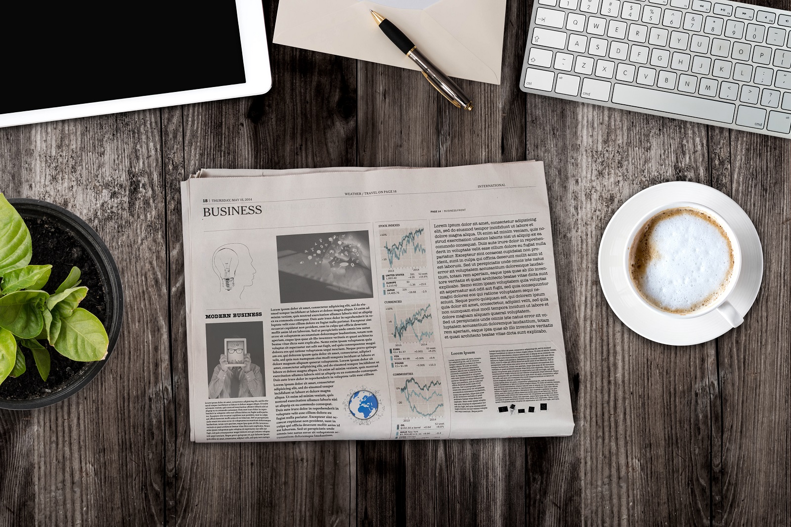 A top down shot of a table with a newspaper, coffee and keyboard on it.