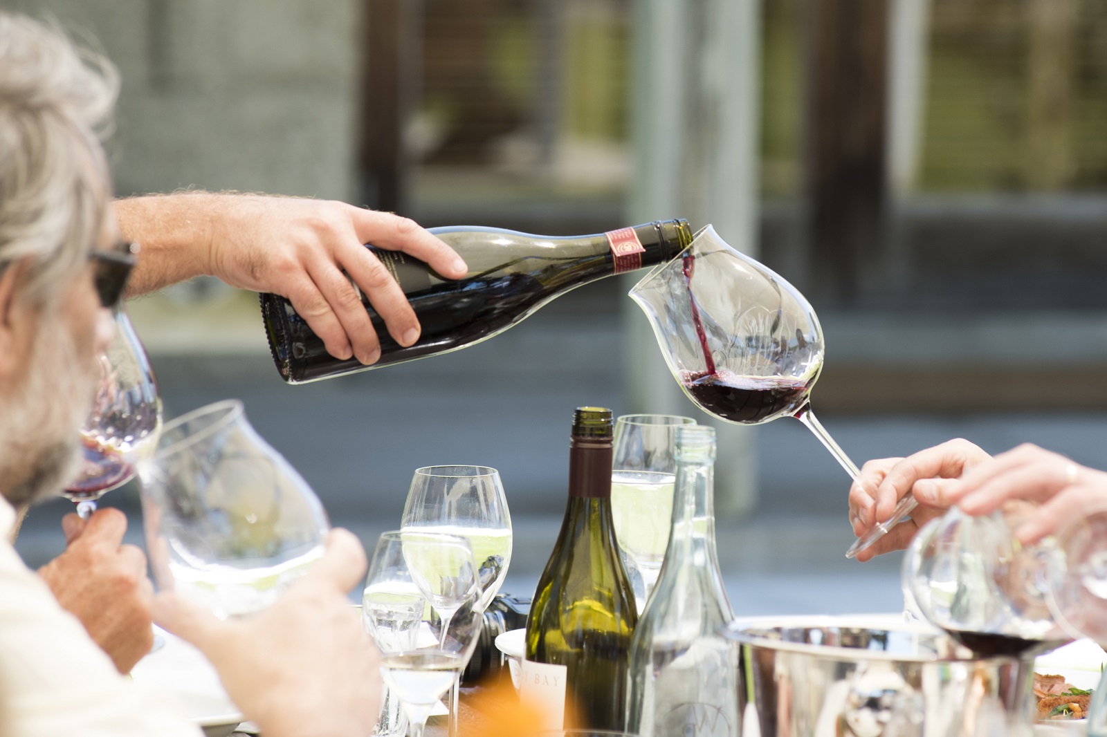 A bottle pouring pinot noir into a glass.