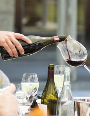A bottle pouring pinot noir into a glass.